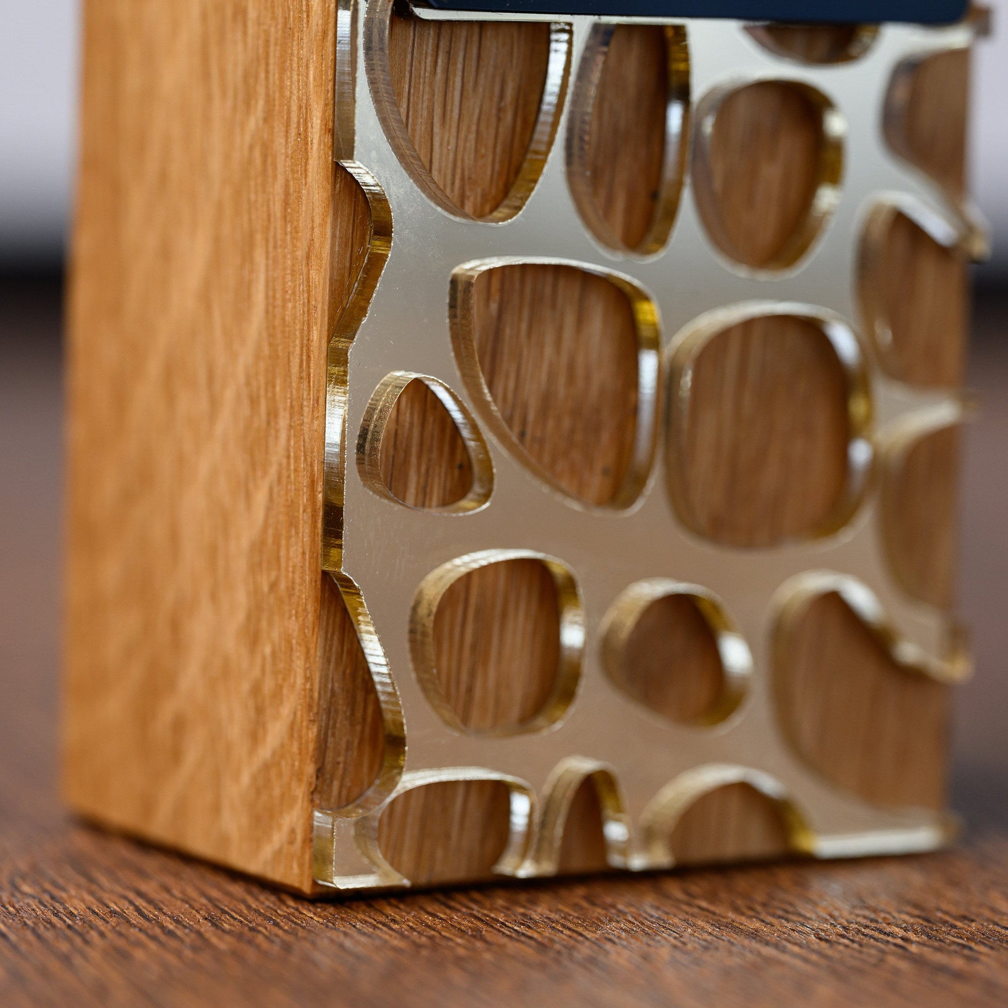 Lower corner of the award where the gold acrylic lattice meets the plain oak side of the column