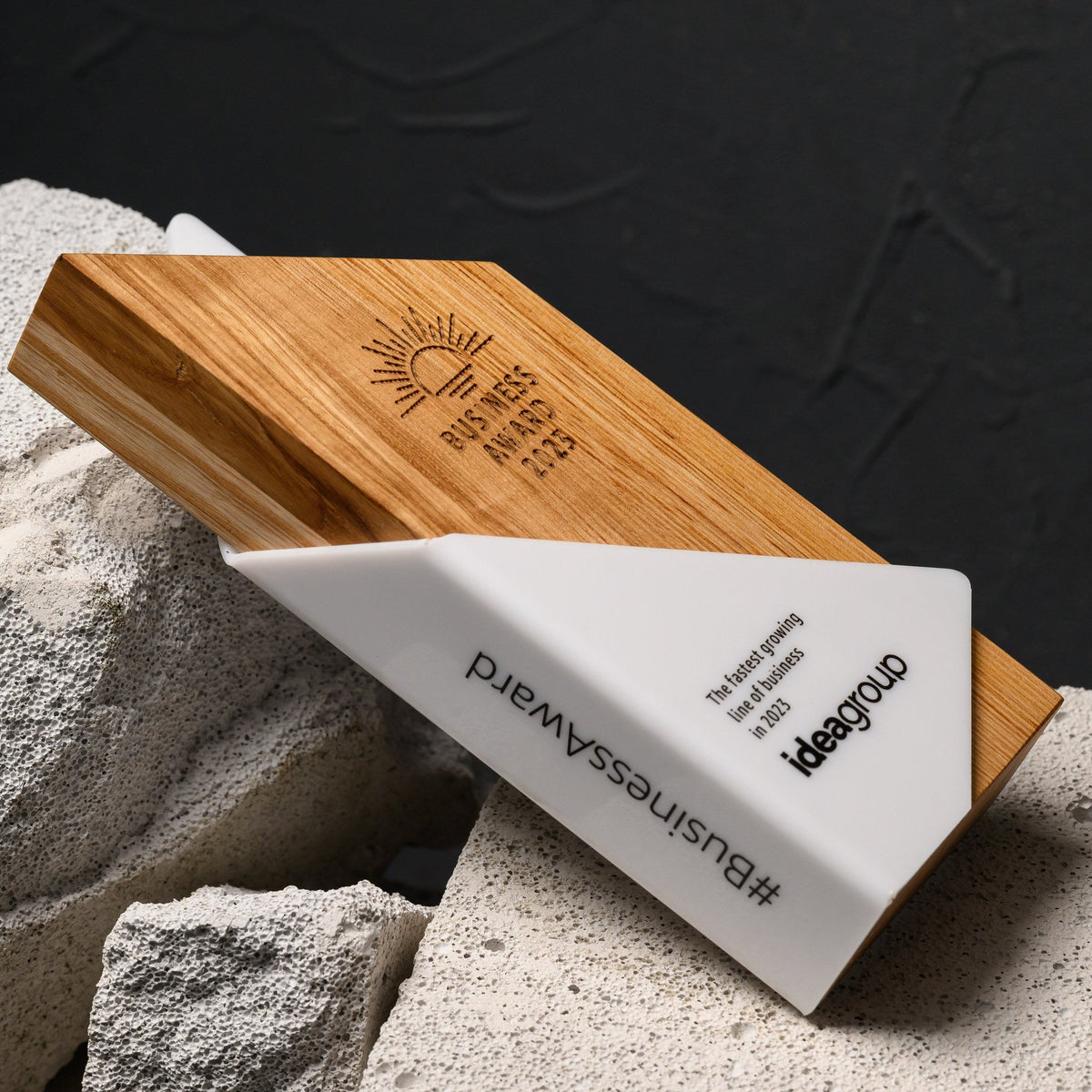 Award lying at an angle on stone, showing the engraved oak face and the acrylic wrap together
