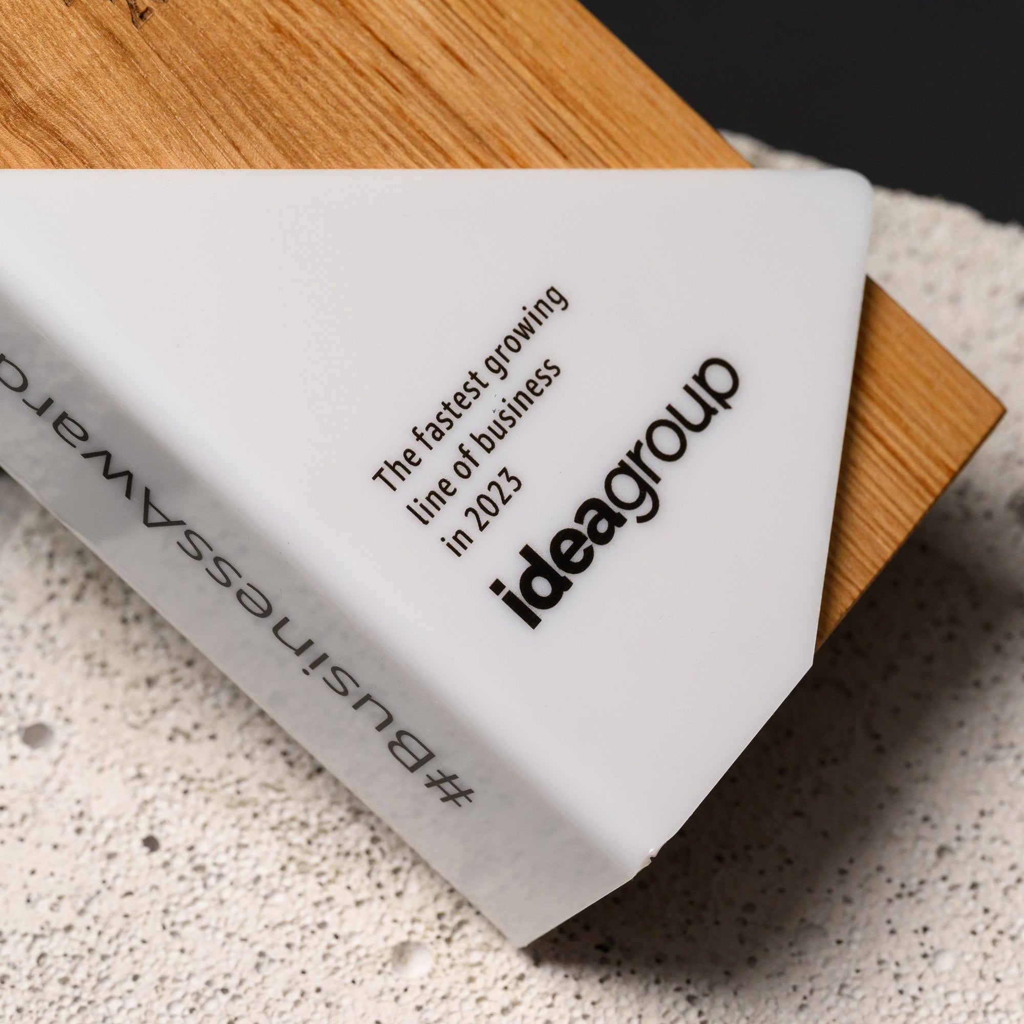 Close view of the printed logo and citation on the white acrylic, with oak grain behind
