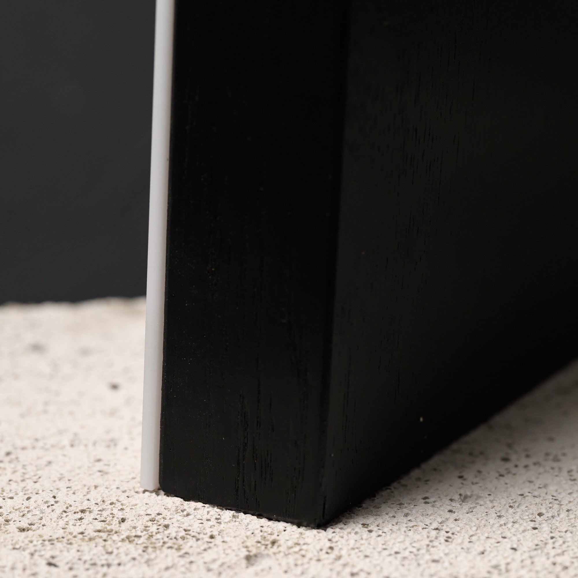 Macro of the blackened oak base showing its grain where it meets the stone surface