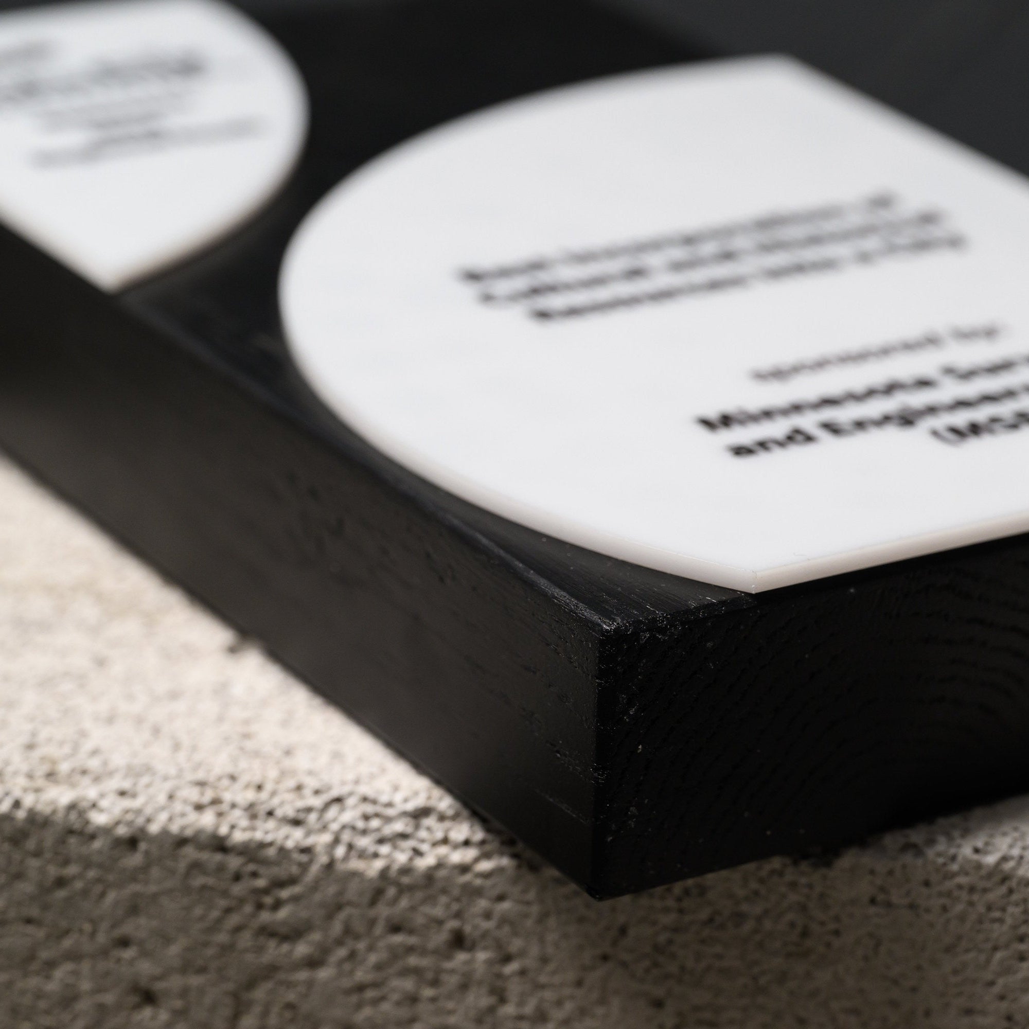 Angled macro of the black oak frame and the thickness of the raised acrylic disc