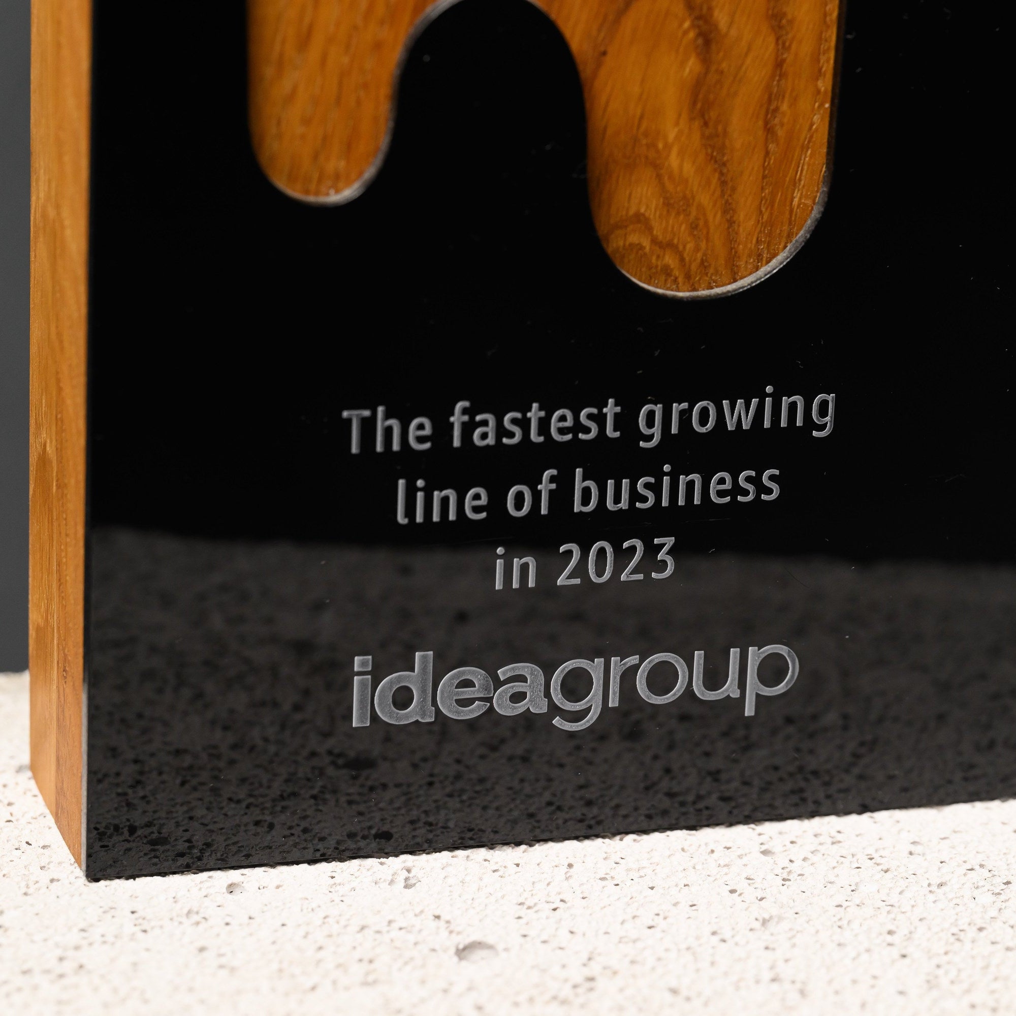 Lower black acrylic panel with a frosted engraved citation and logo, framed by the oak edge