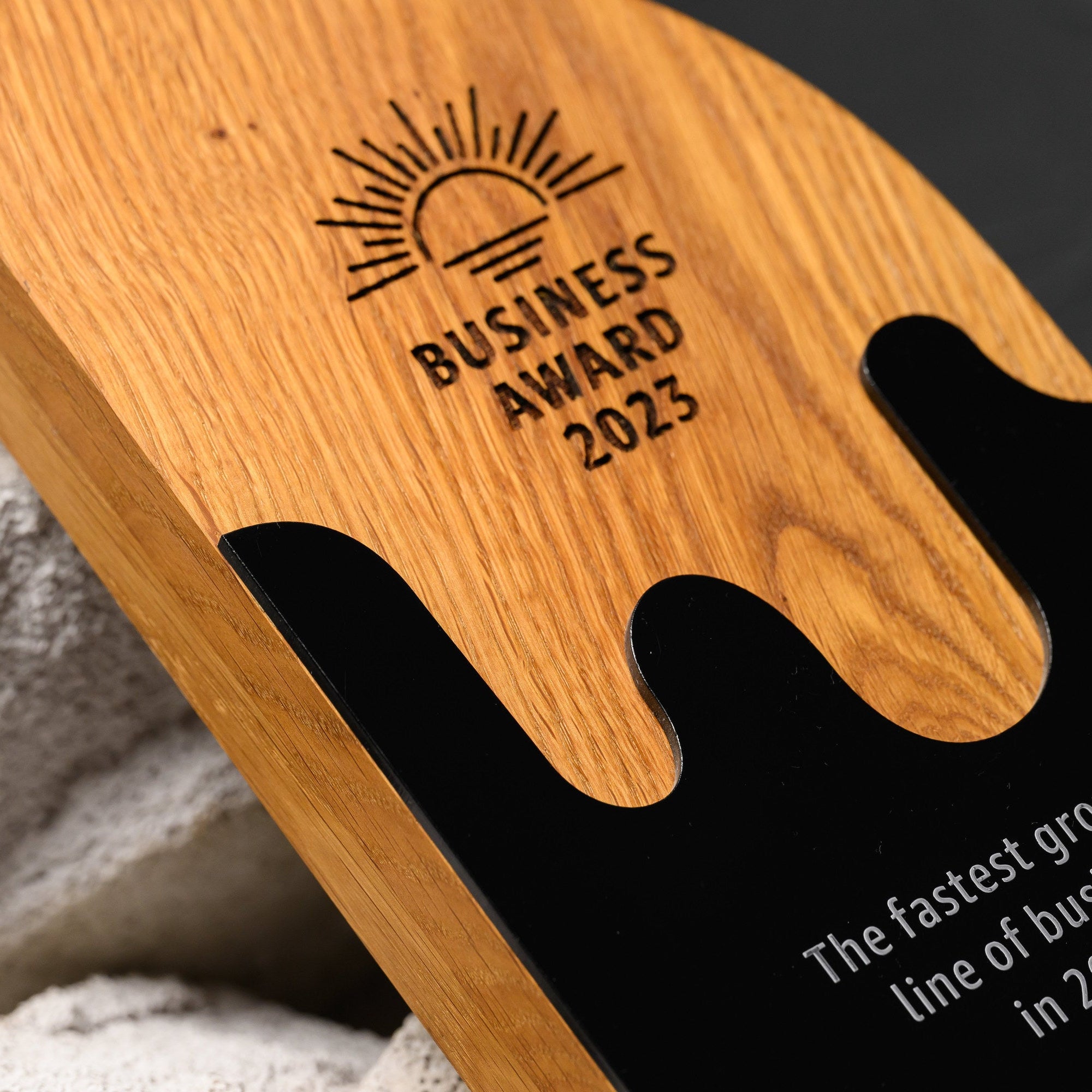 Award lying on stone, showing the engraved oak arch above the curving acrylic boundary
