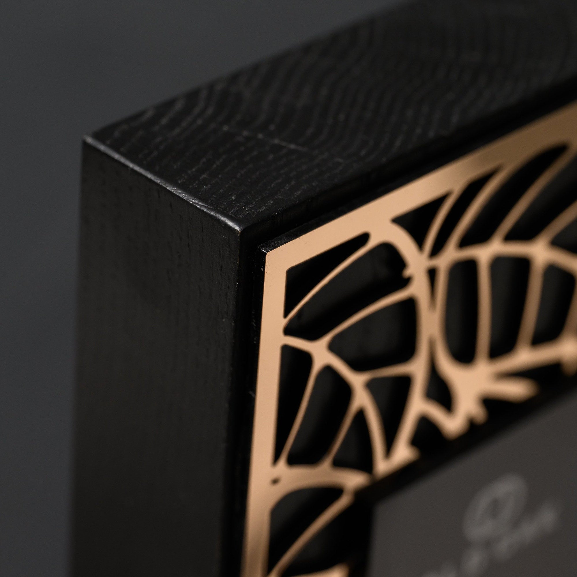 Top corner where the black oak edge frames the gold lattice against a dark background