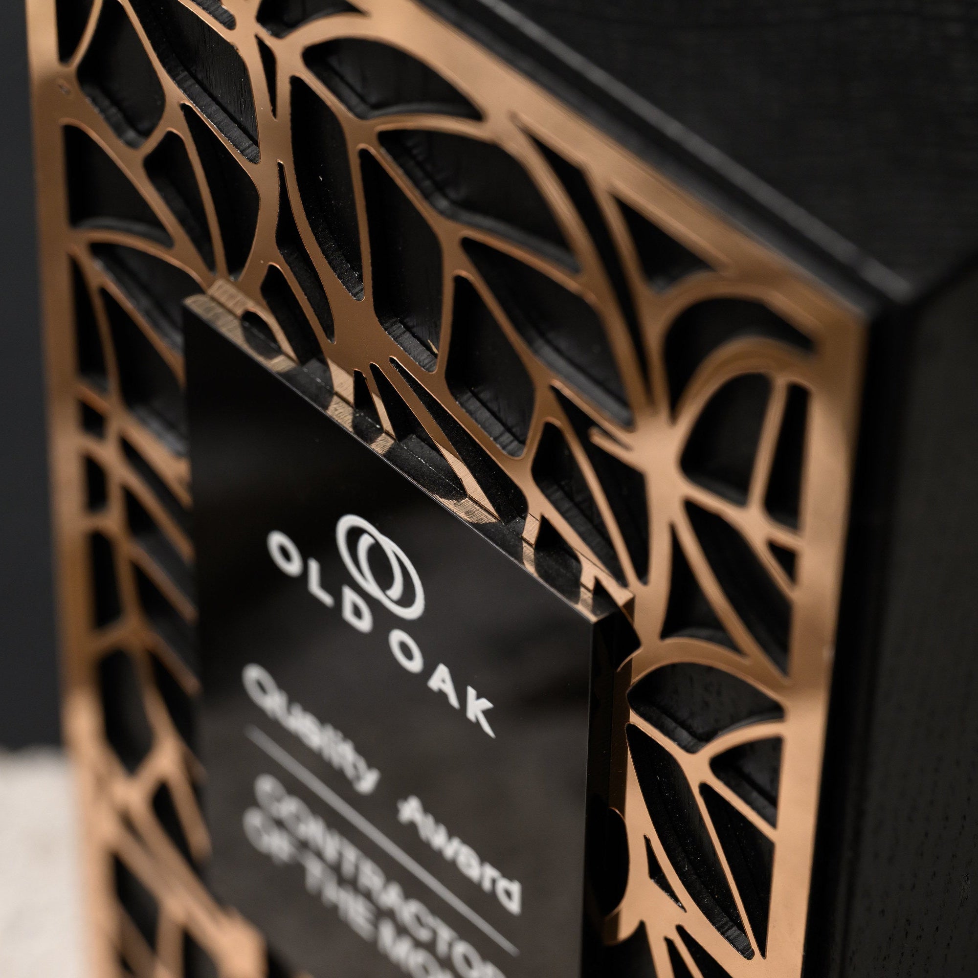Angled macro of the gold lattice meeting the edge of the raised black acrylic plate