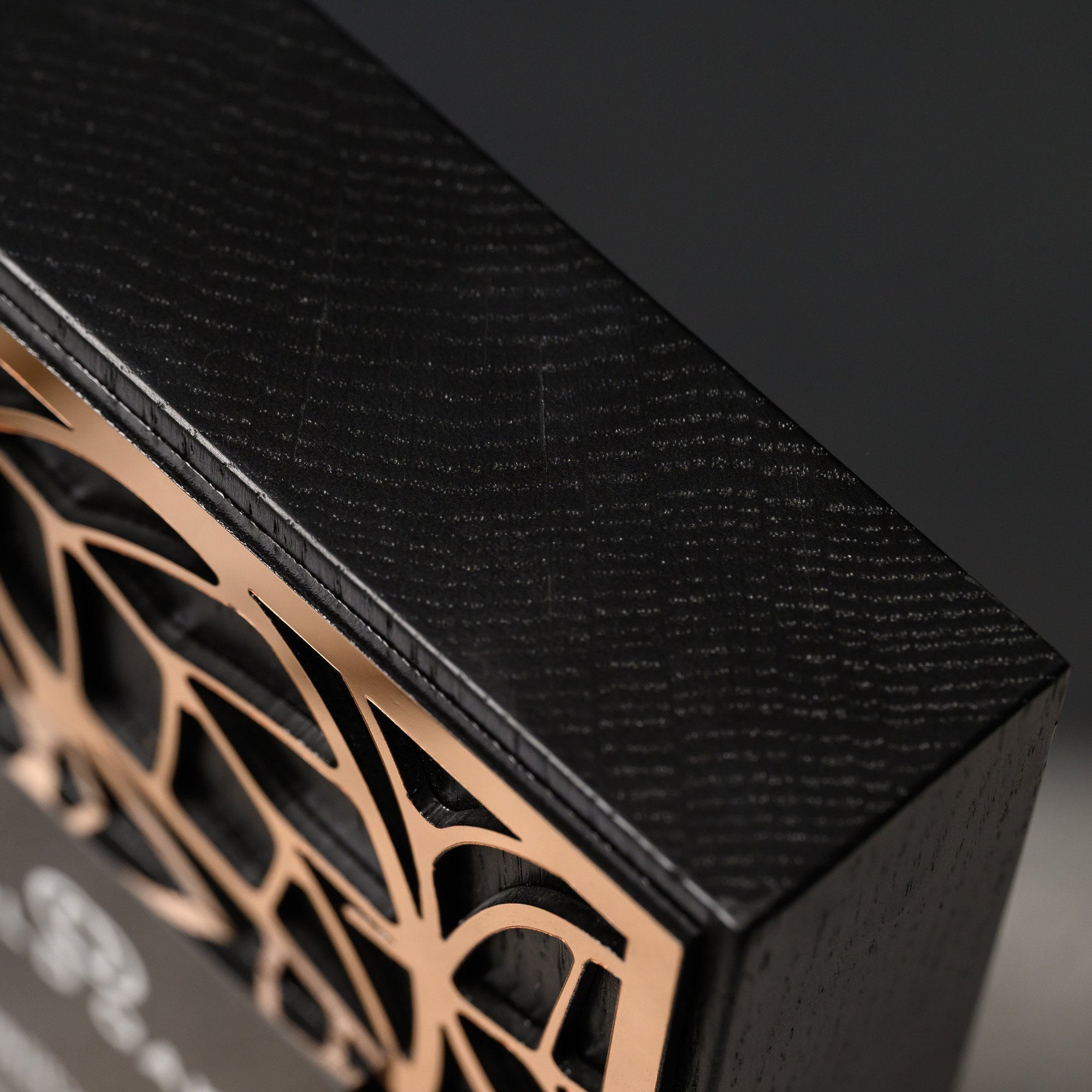 Top edge of the blackened oak block showing its grain beside the gold acrylic layer