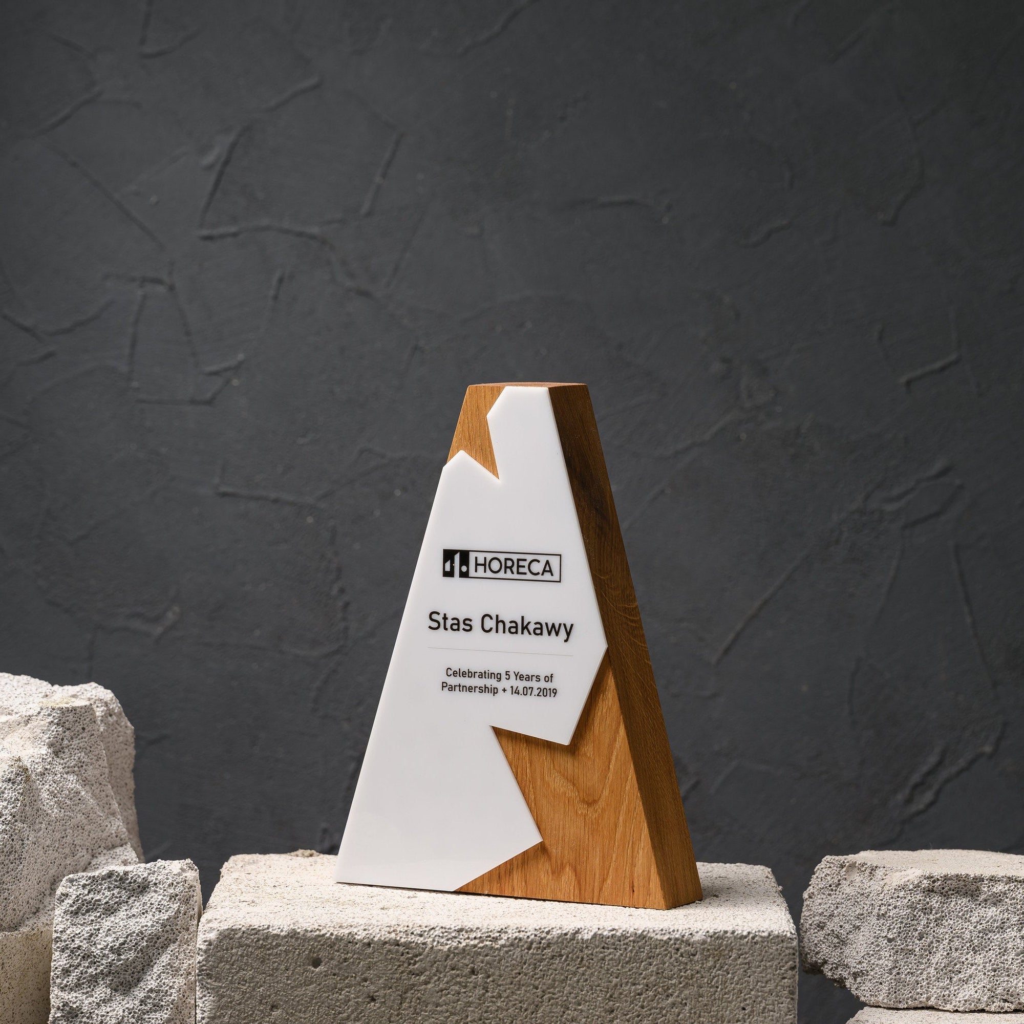 Oak and white acrylic partnership award shaped like a peak, standing on a stone plinth