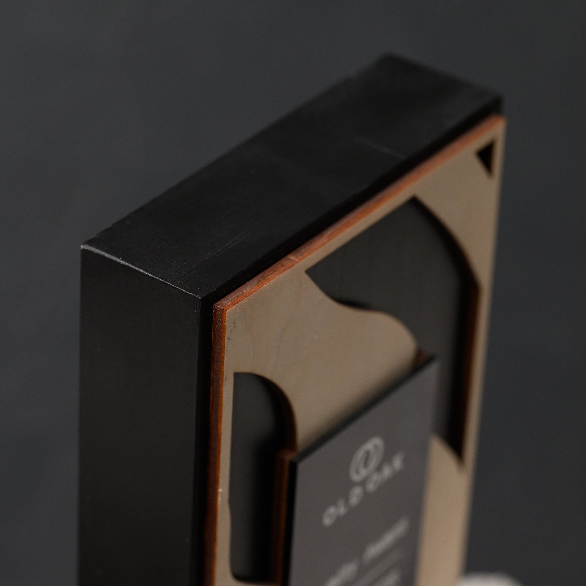 Side profile of the upper corner showing the depth of the black oak body against a dark wall