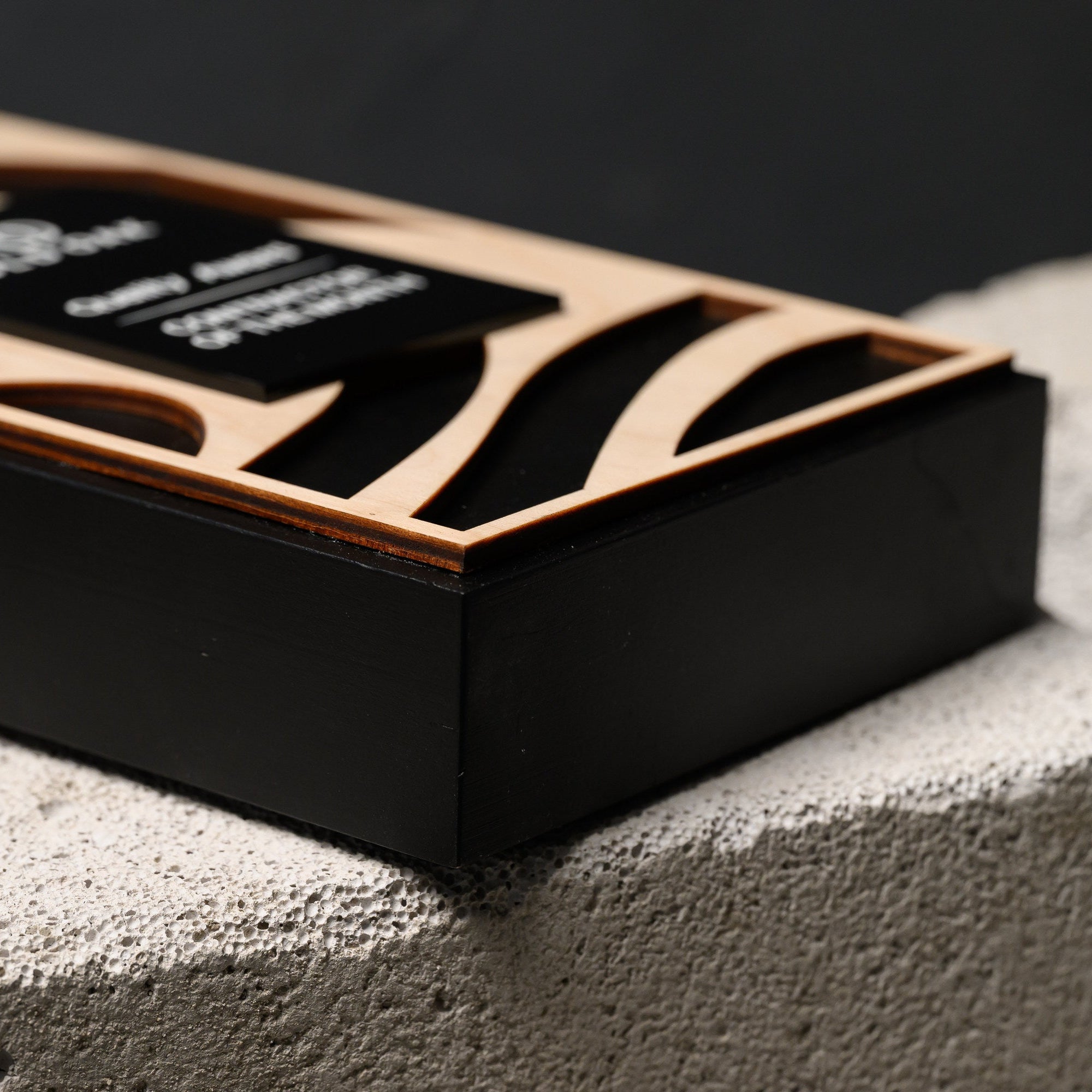 Low angle of the plaque lying flat, showing the thickness of the black oak base and raised panel