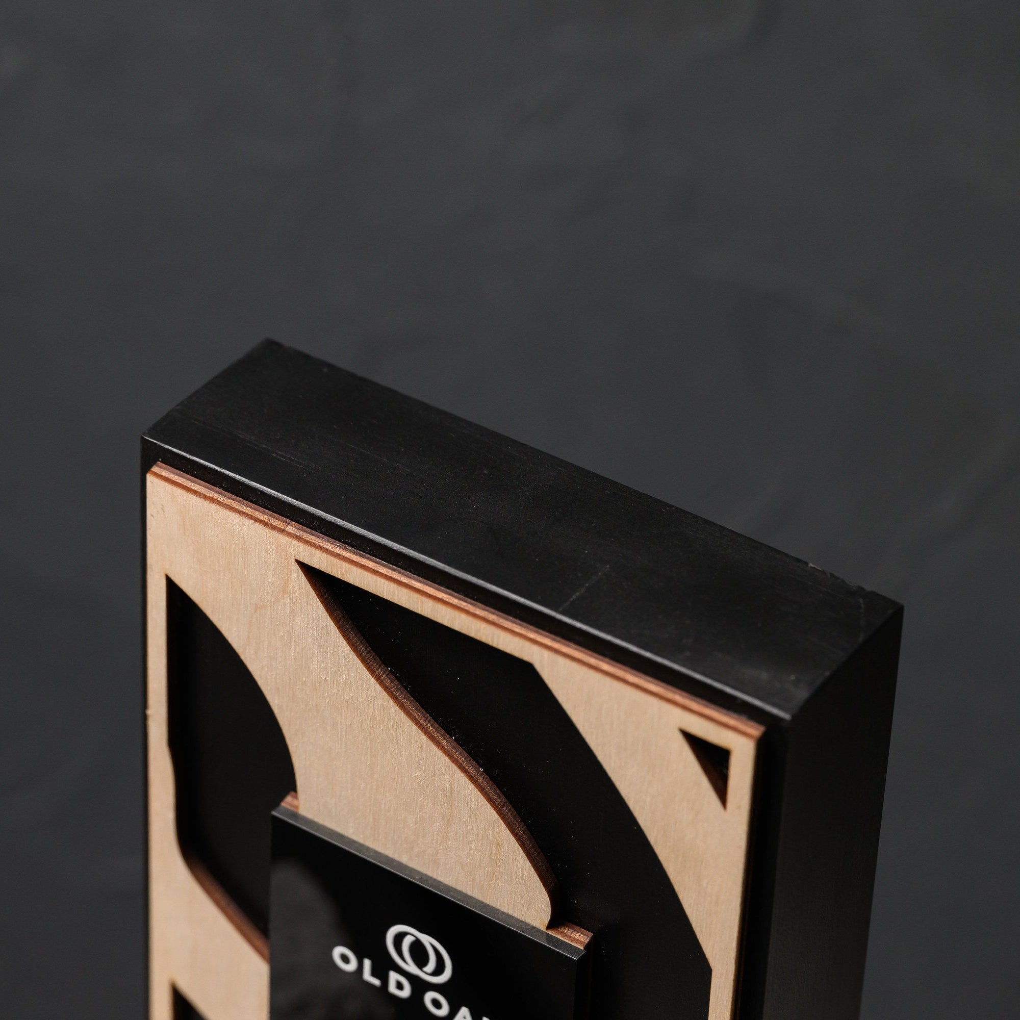 Top corner of the award showing the black painted oak frame above the plywood front panel