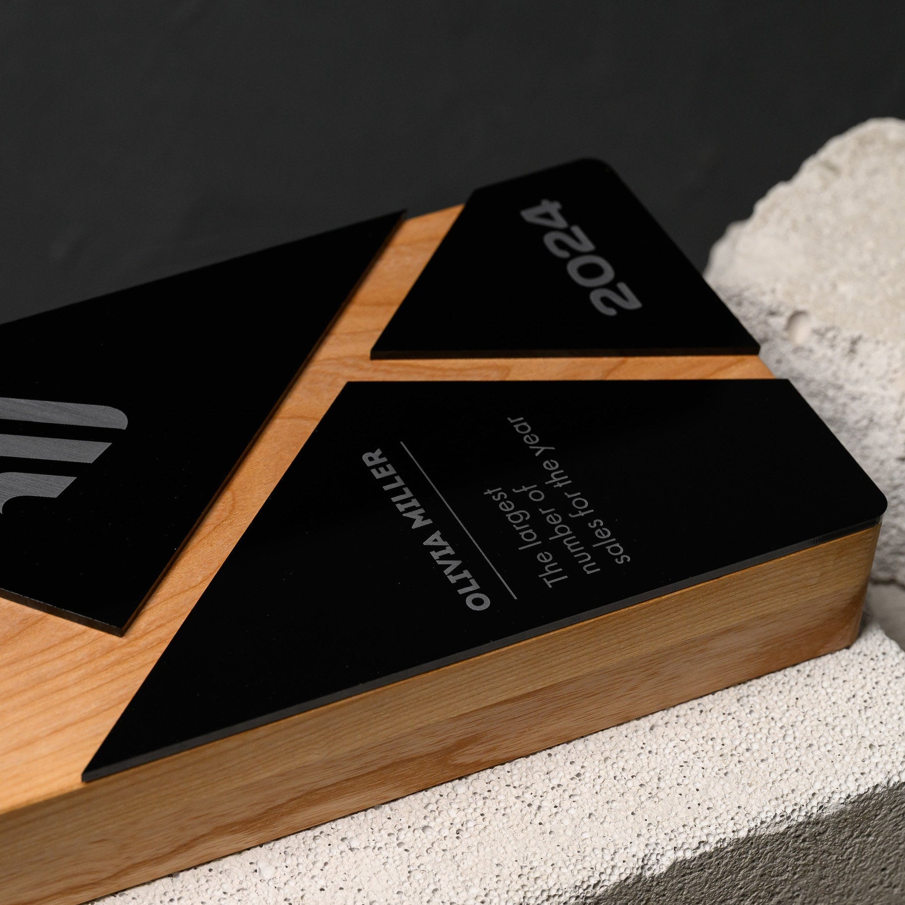 Award lying at an angle on stone, showing the full geometric layout of wood and acrylic