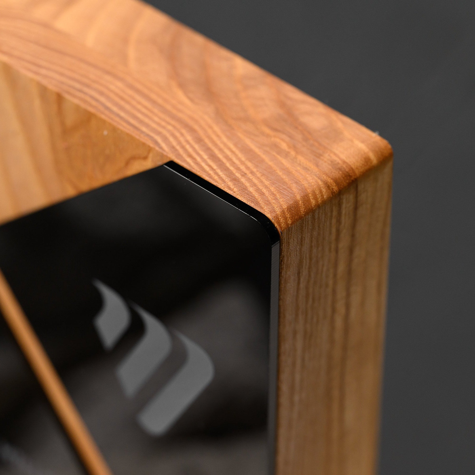 Top edge of the oak body showing grain and the rounded corner above the acrylic panel