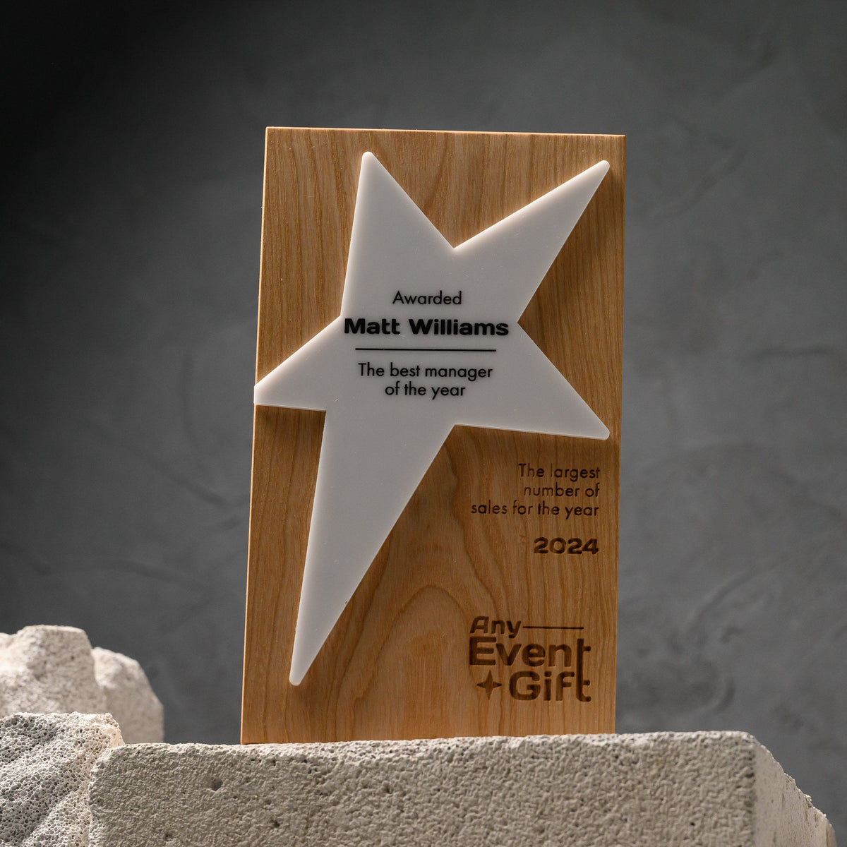 Oak star award standing on concrete blocks against a dark wall, showing its full proportions