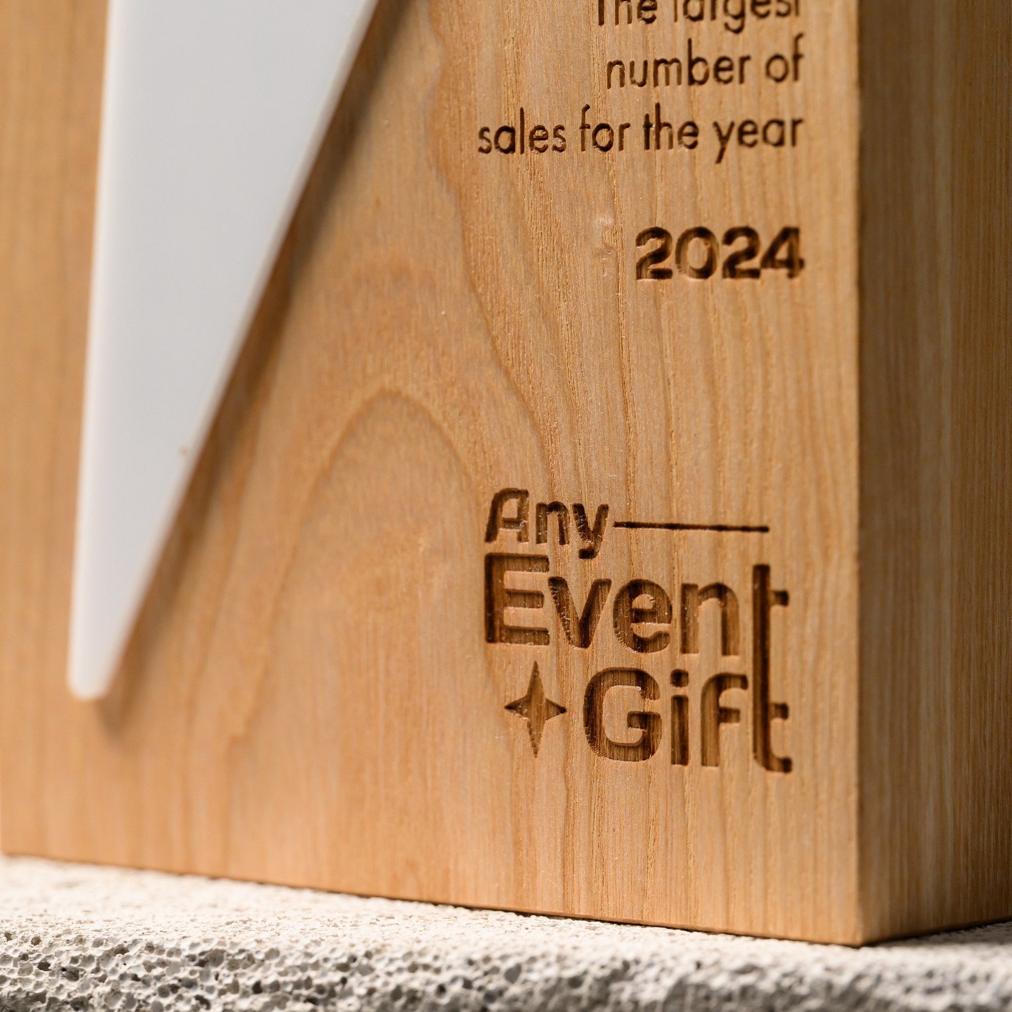 Lower section of the star award where the acrylic tail meets the engraved text on oak