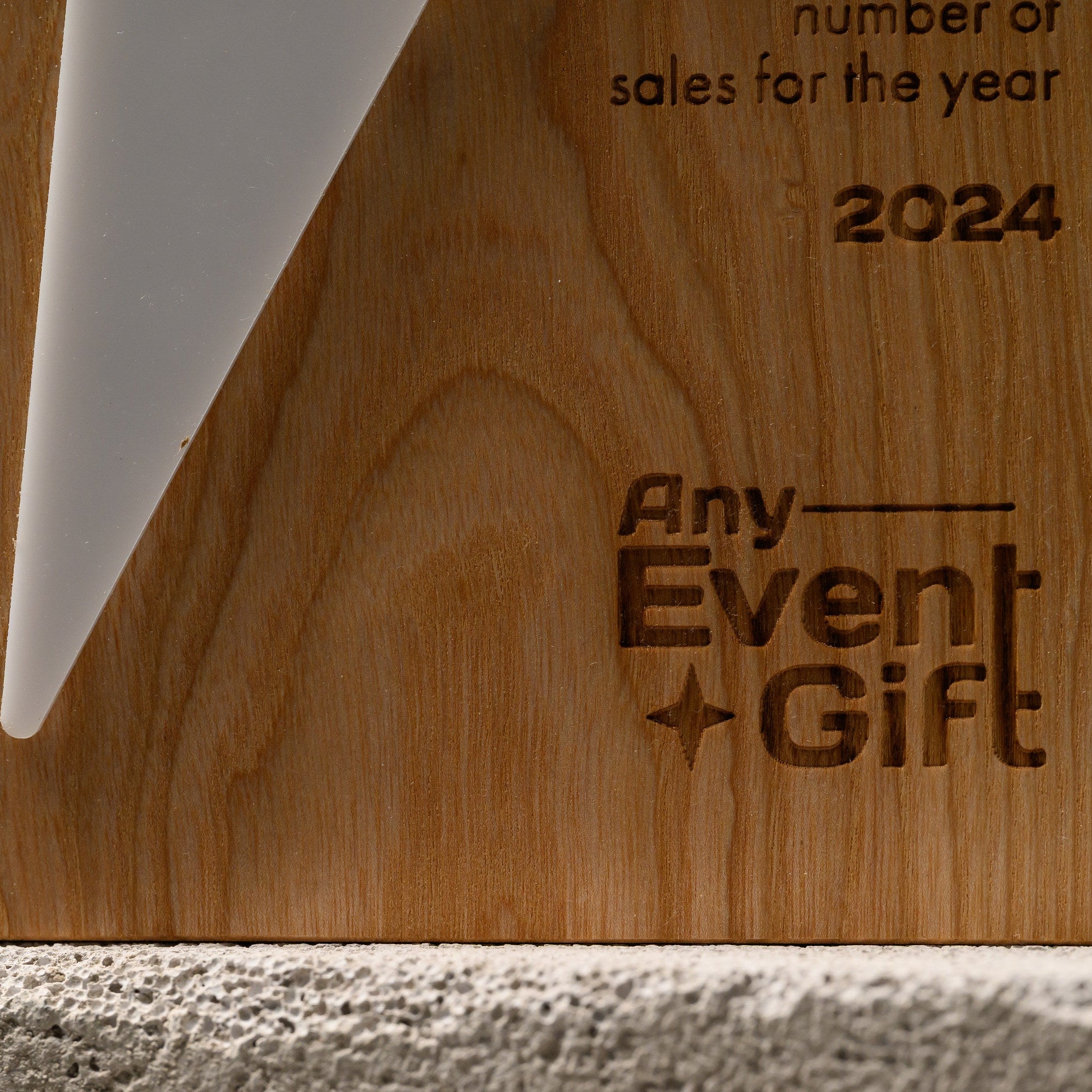 Oak and white acrylic star award lying flat on stone, with engraved wording beside the printed star