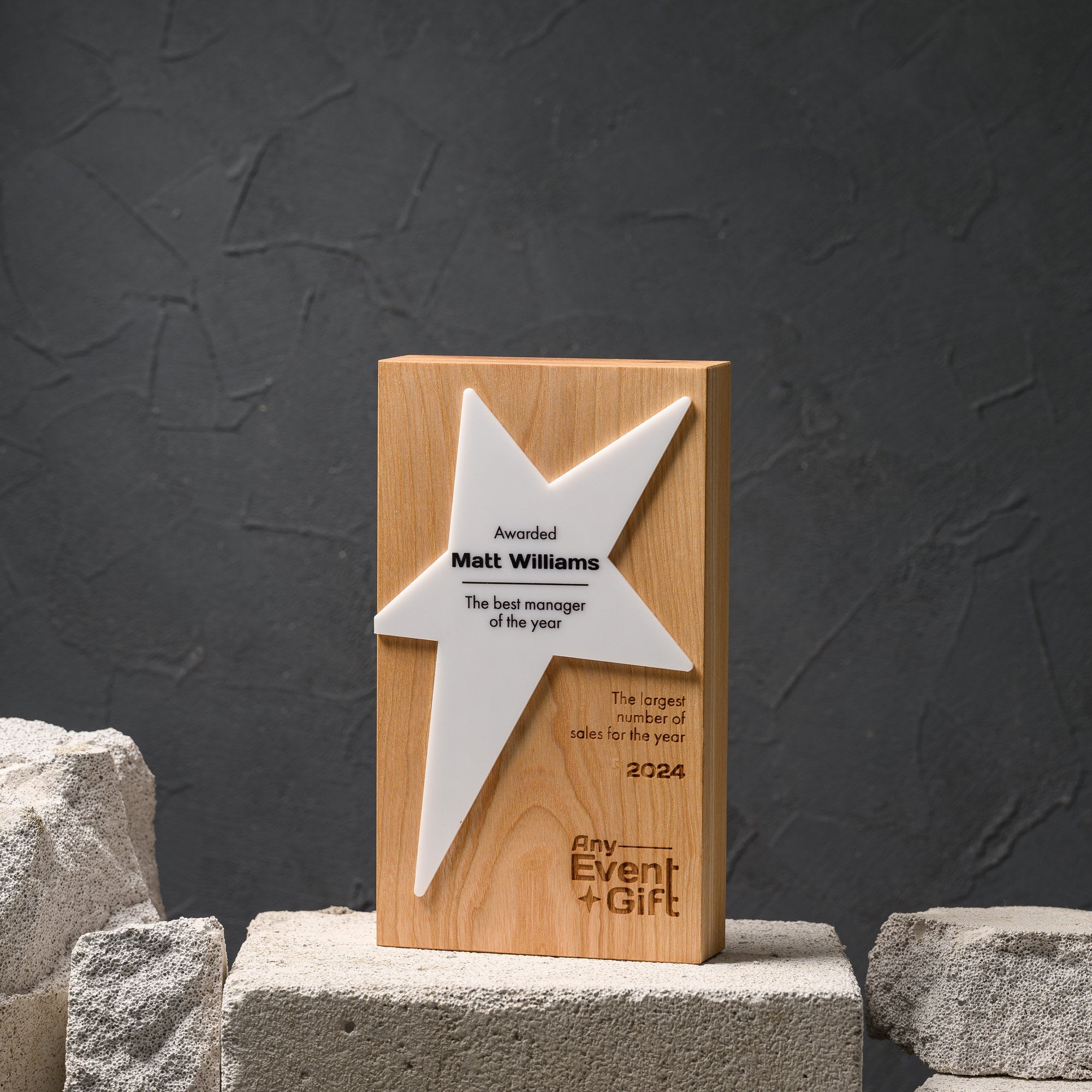 Star award with a white acrylic star mounted on an engraved oak block, front view on a stone plinth