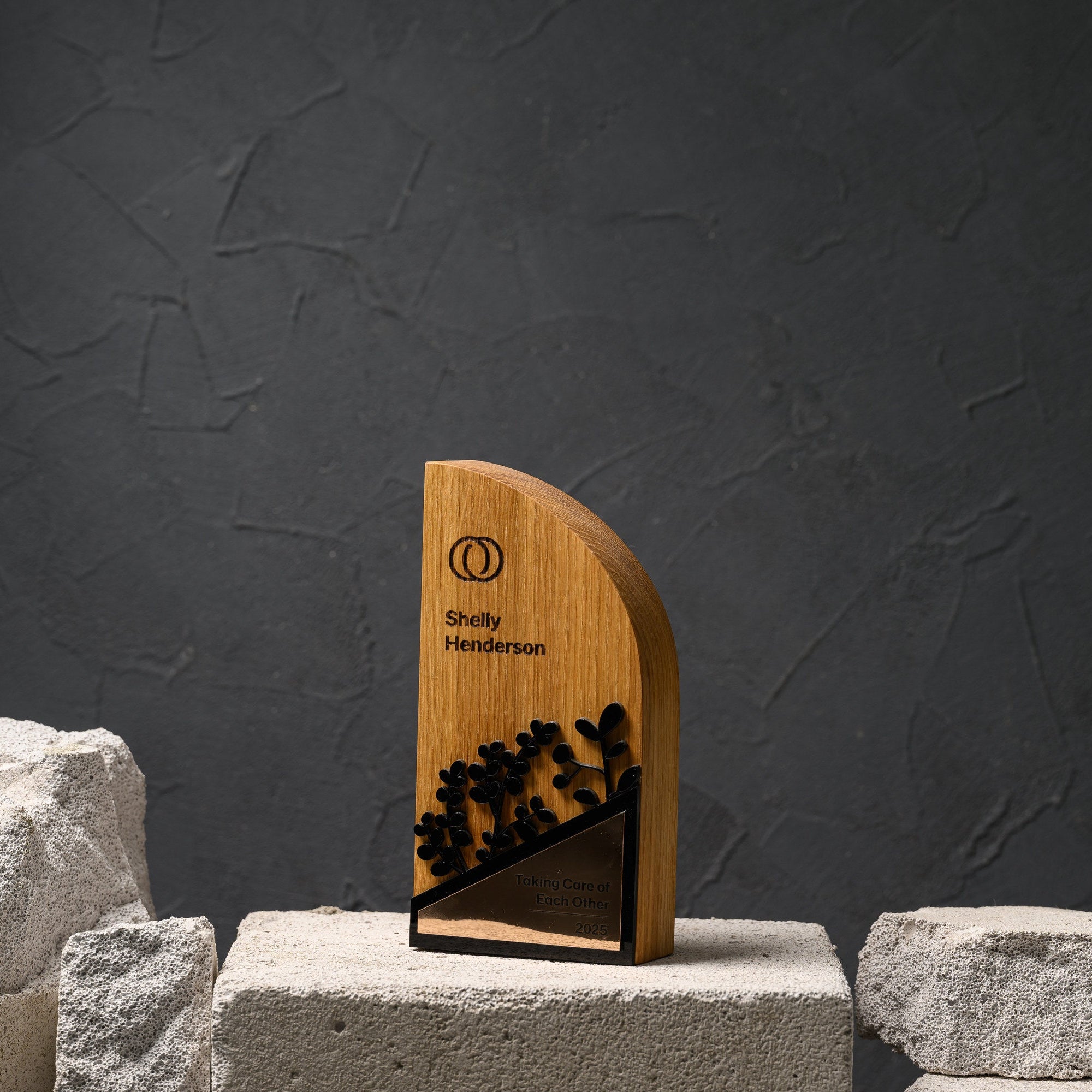 Oak sustainability award displayed on concrete blocks against a dark textured wall
