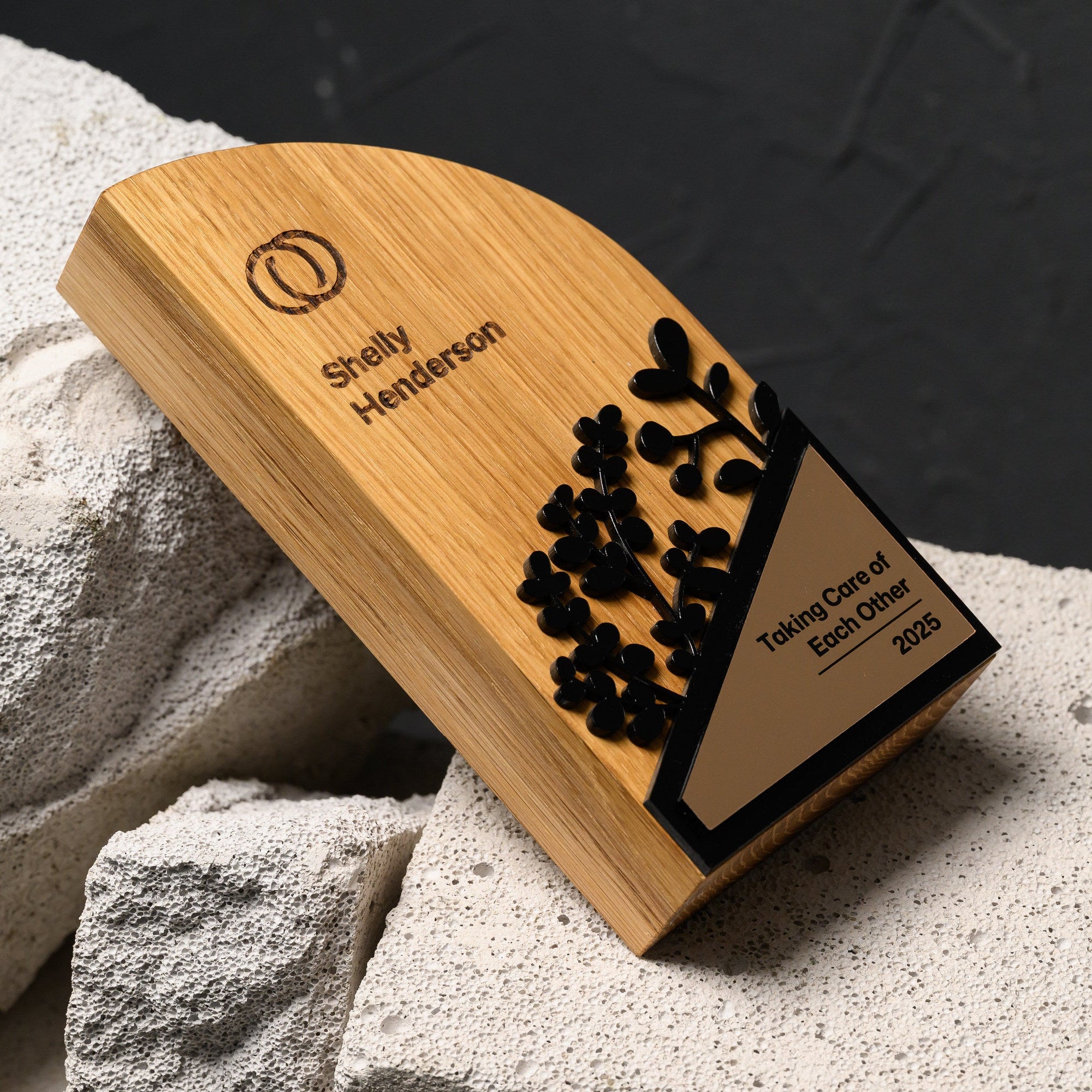 Oak award lying at an angle on stone, with the engraved upper panel and gold plate both visible
