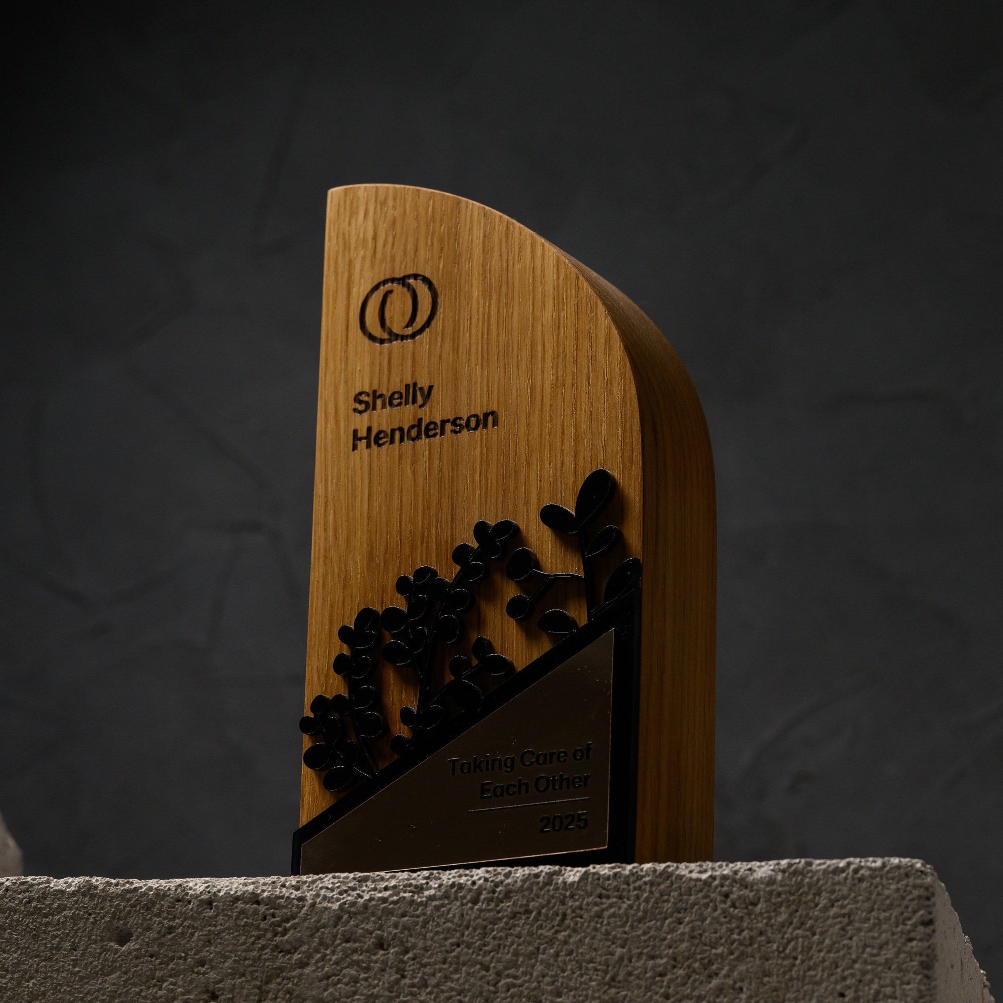Oak award lit from the side, showing its curved profile and the raised black acrylic branches