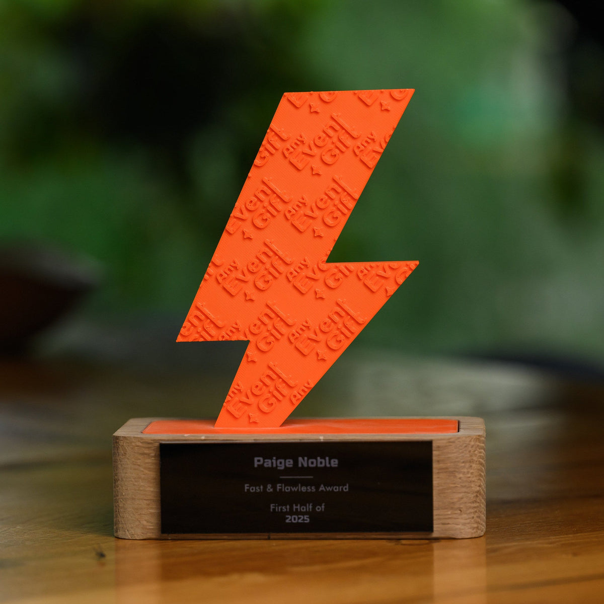Custom 3D printed trophy with an orange lightning bolt figure on a solid oak base, viewed head on