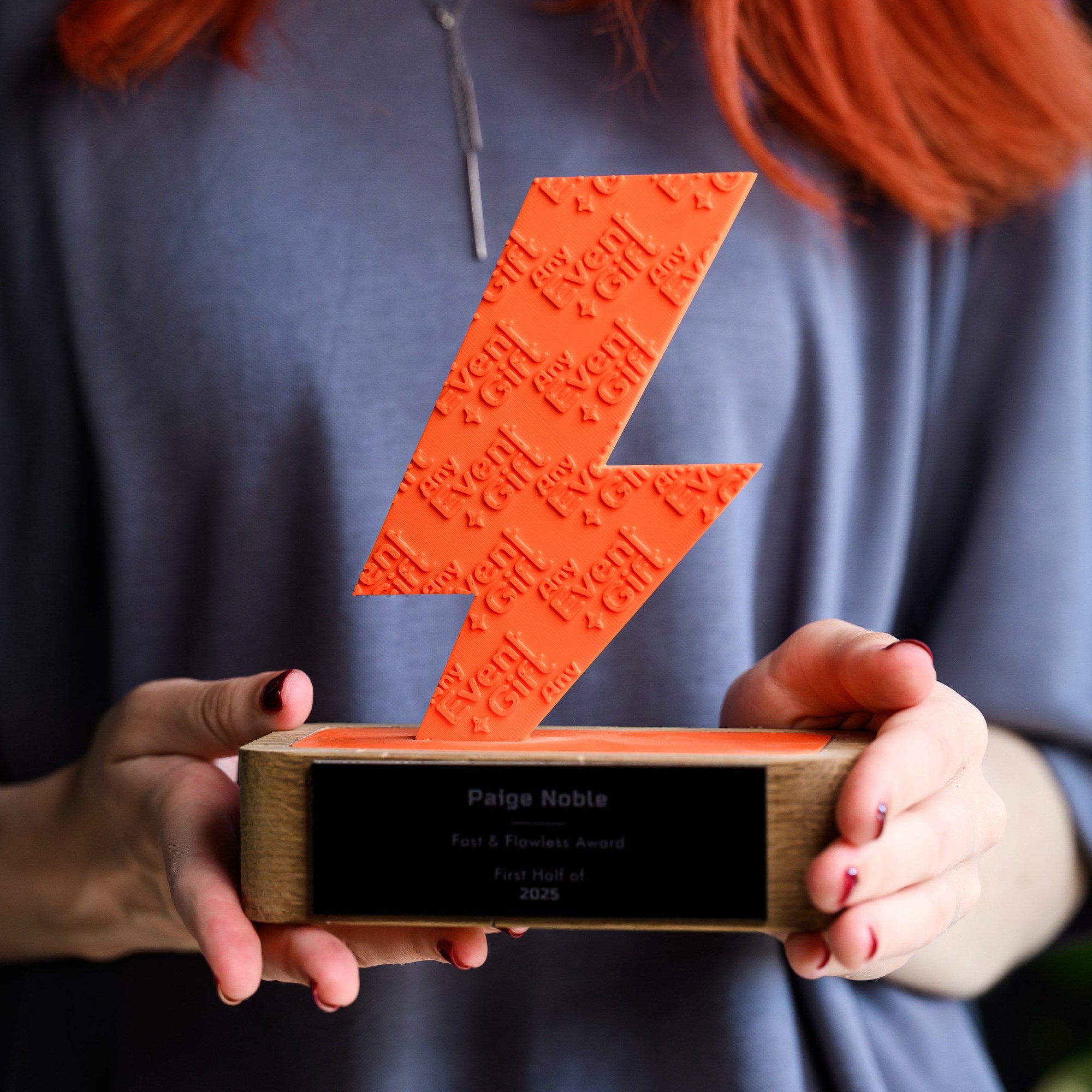Person holding the 3D printed award with both hands, showing its scale against the body