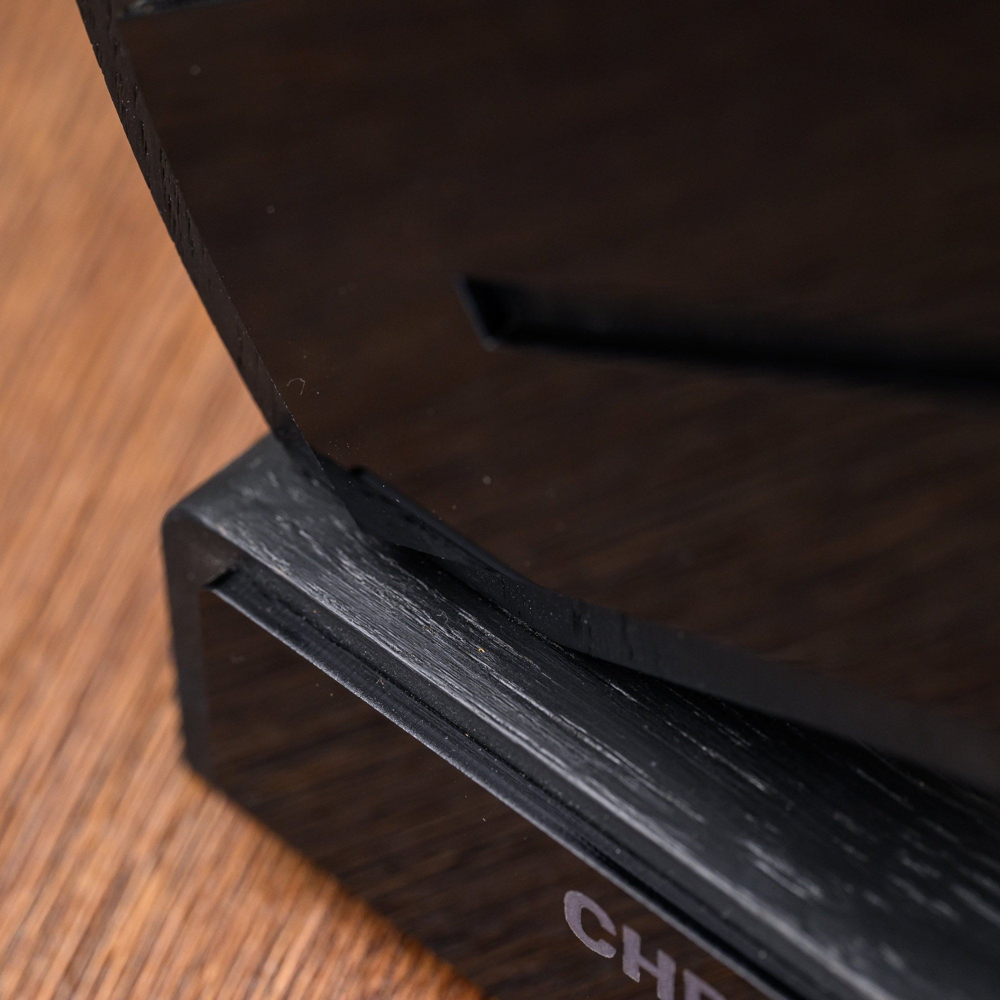 Junction between the sculpted award body and the black oak base, showing the slotted assembly