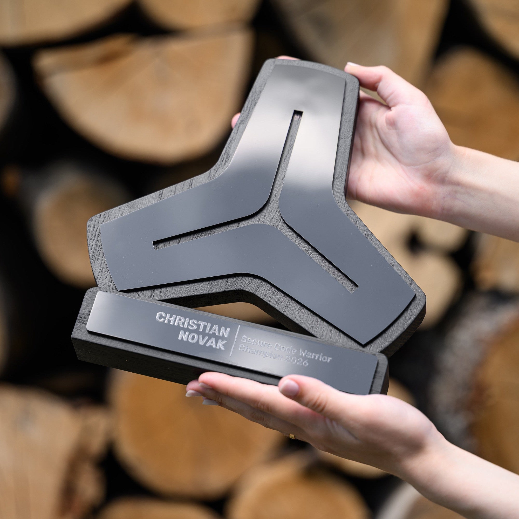 Angled view of the black corporate award held in two hands, showing the layered acrylic front face