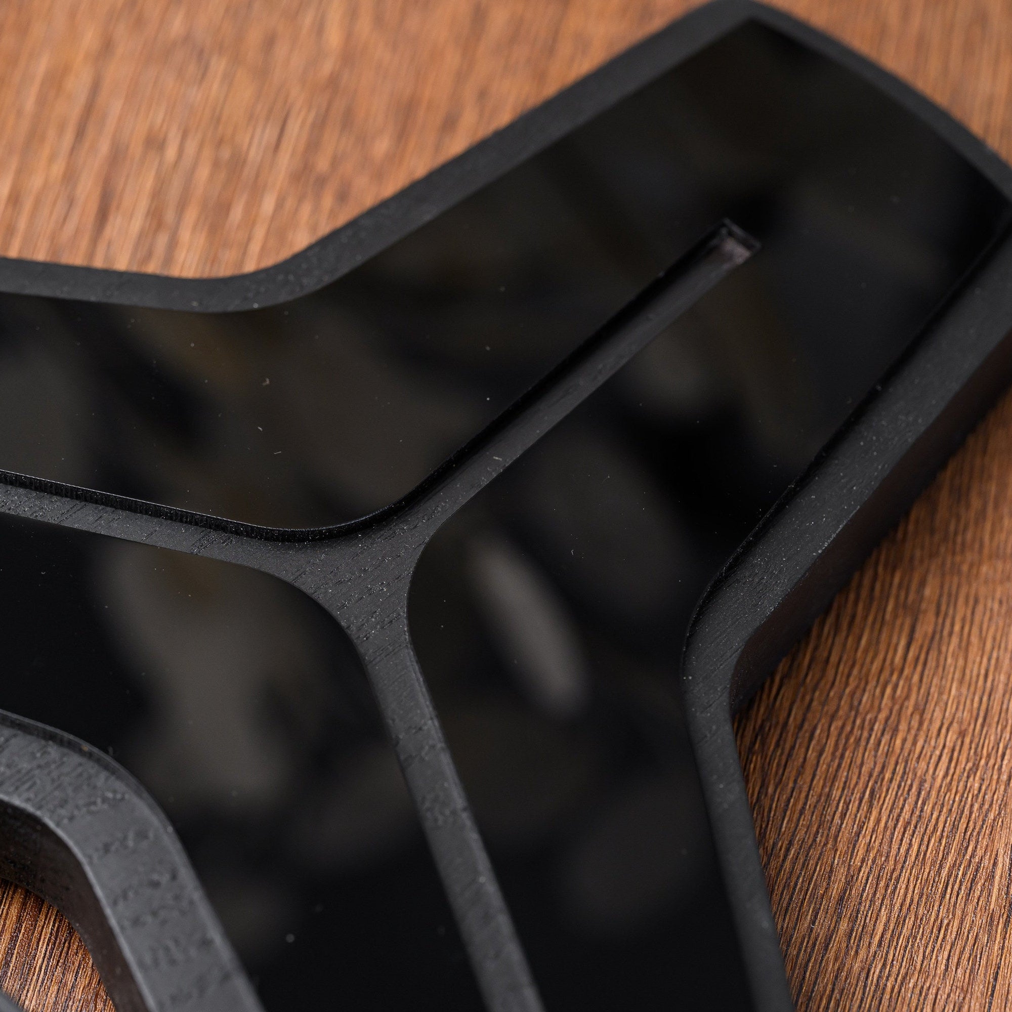 Close-up of the polished black acrylic overlay set into the sculpted black oak body of the award