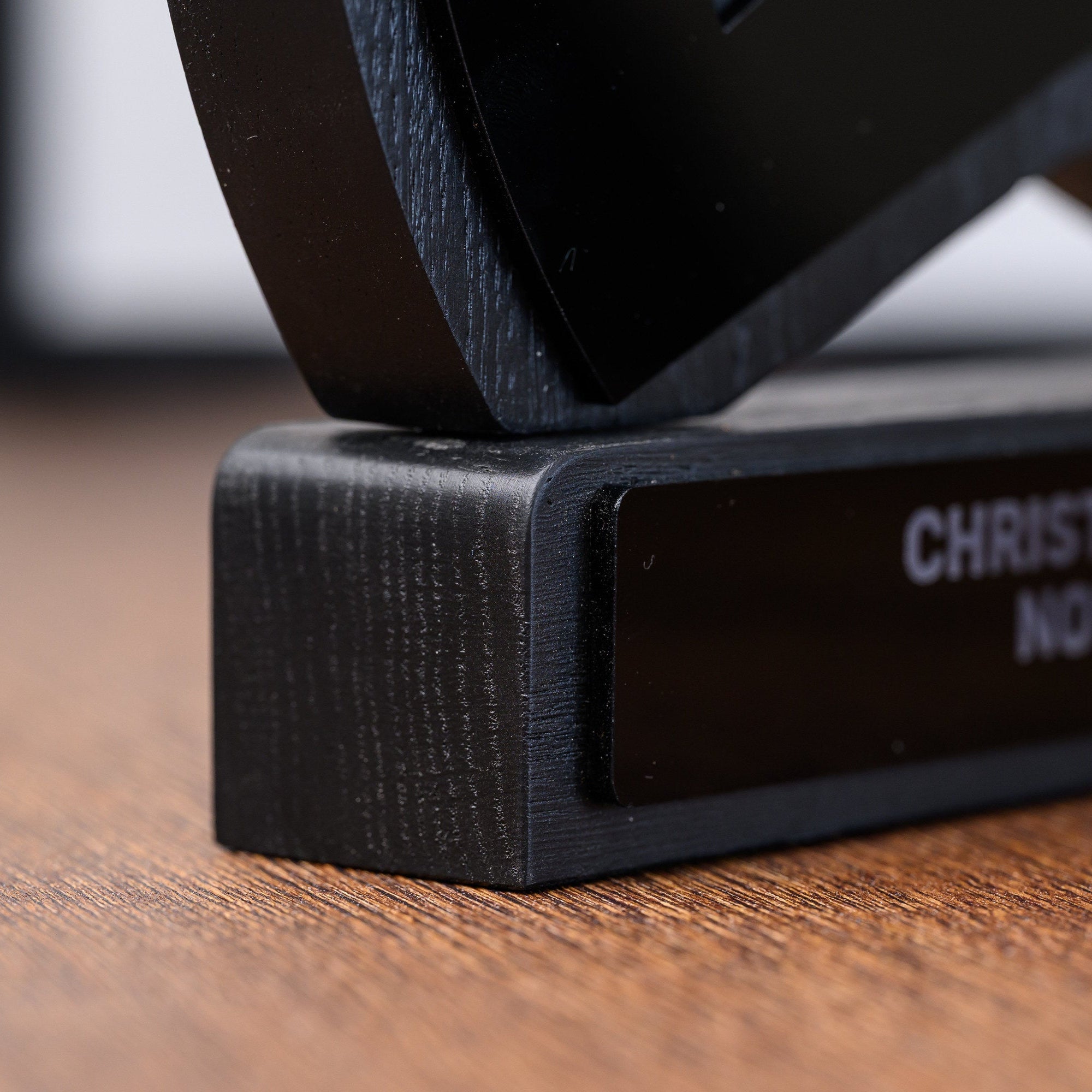 Macro view of the weighted plinth base with the engraved acrylic plate seated in a routed channel