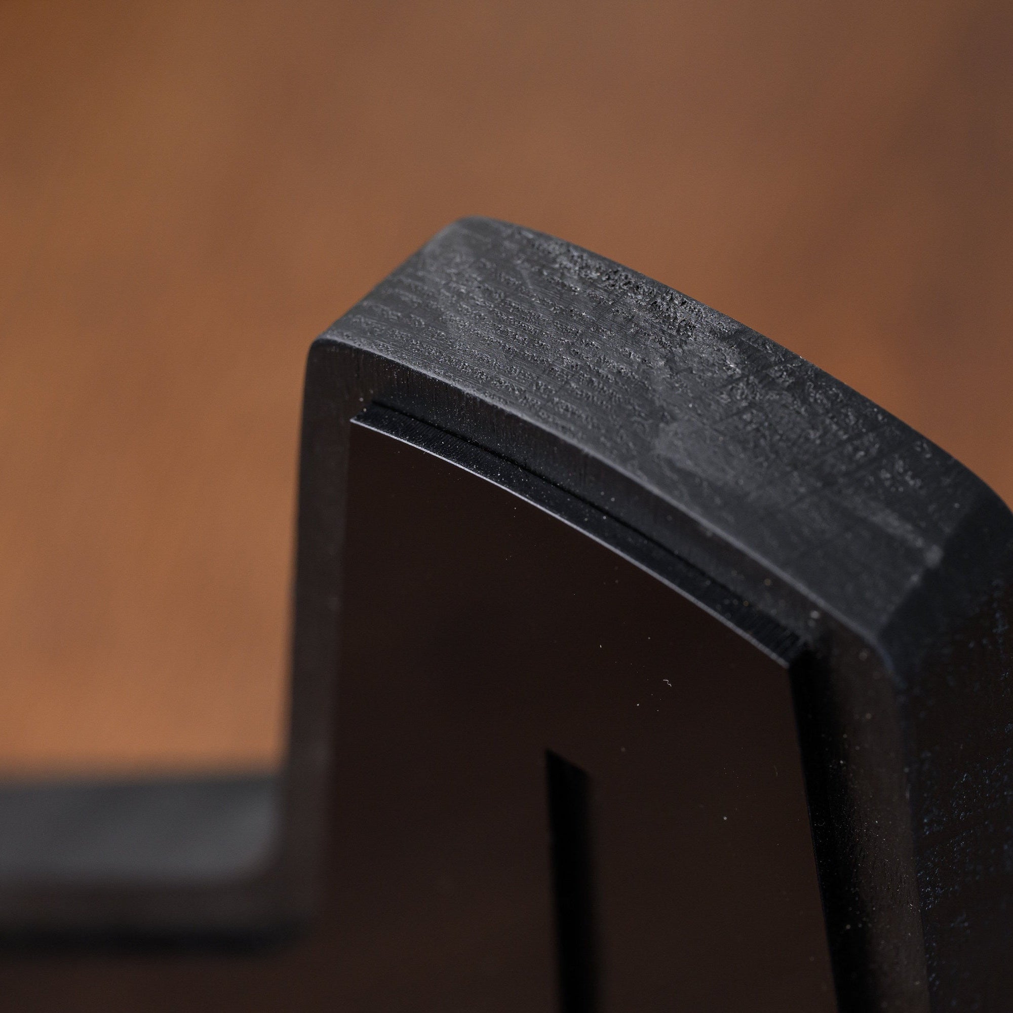 Top corner of the award showing the brushed black oak edge against the glossy acrylic face