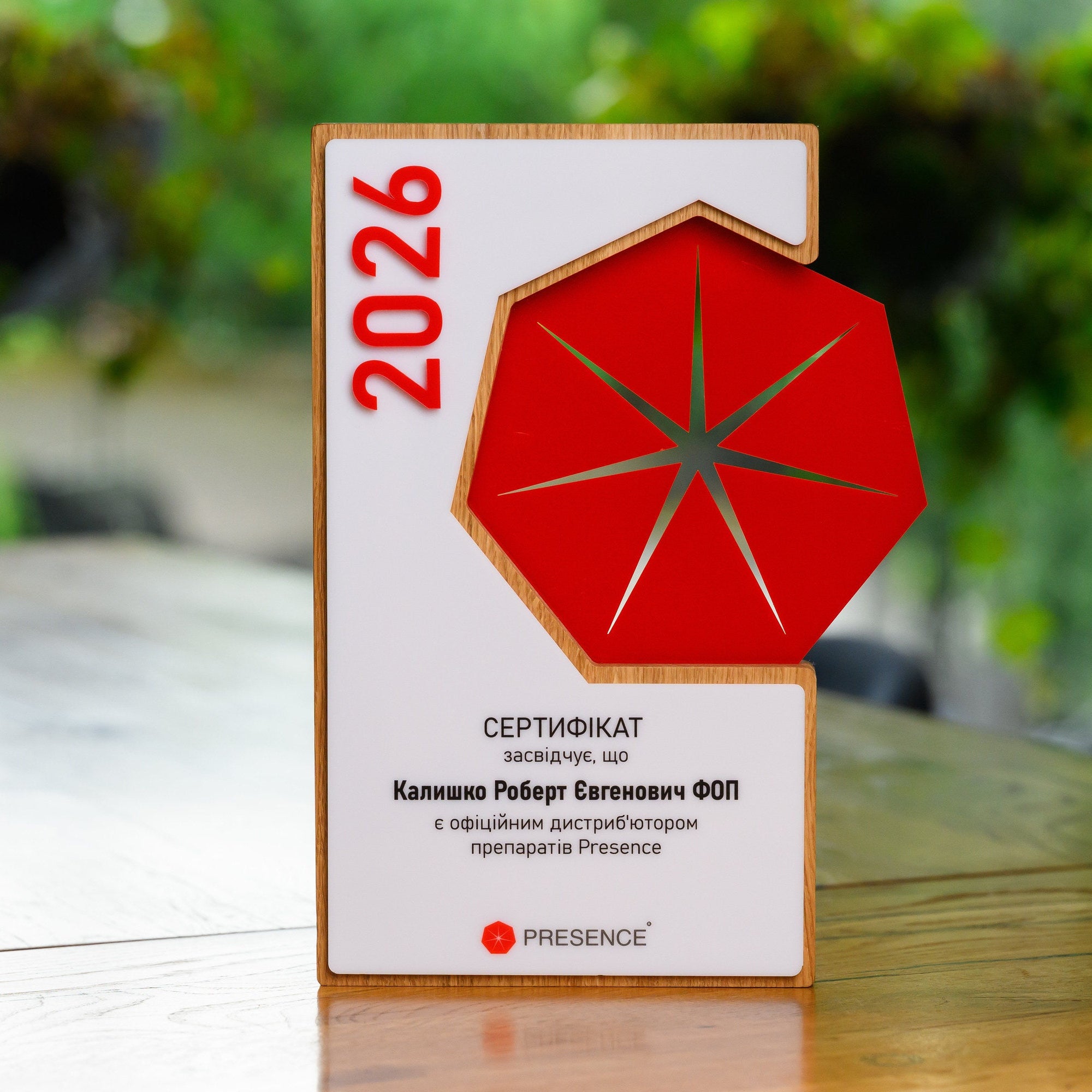 Custom award plaque in oak with white and red layered acrylic, standing upright on a wooden table