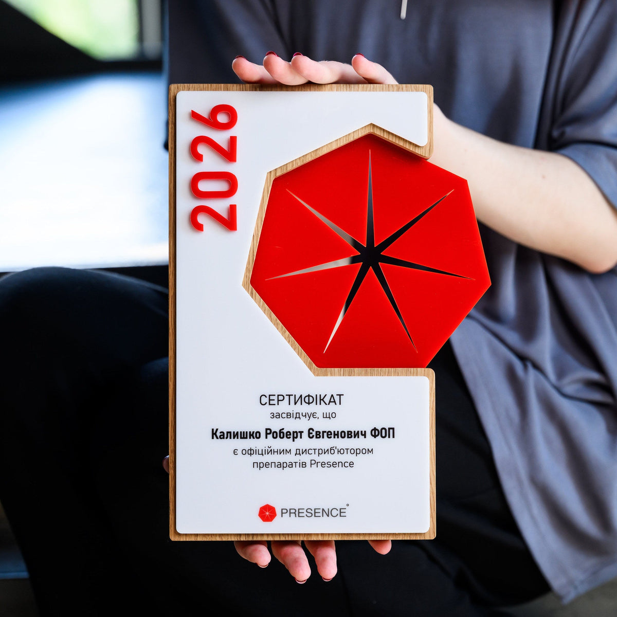 Person holding the layered acrylic award plaque, showing its scale against the body