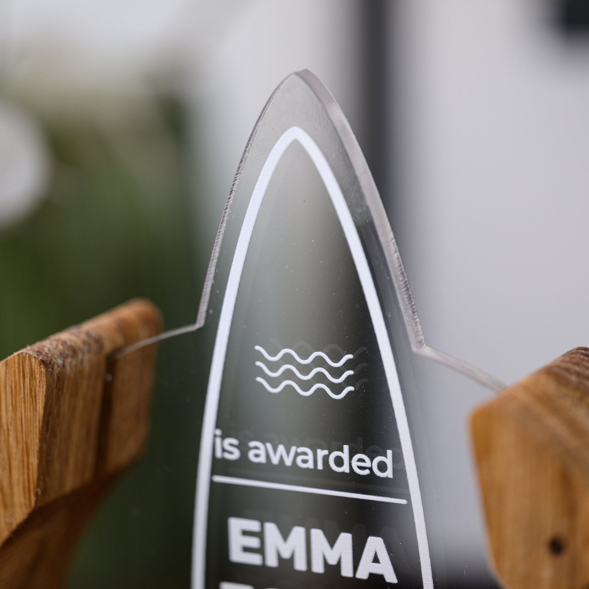 Close-up of the clear acrylic surfboard insert with UV printed wave symbol and awarding line of text