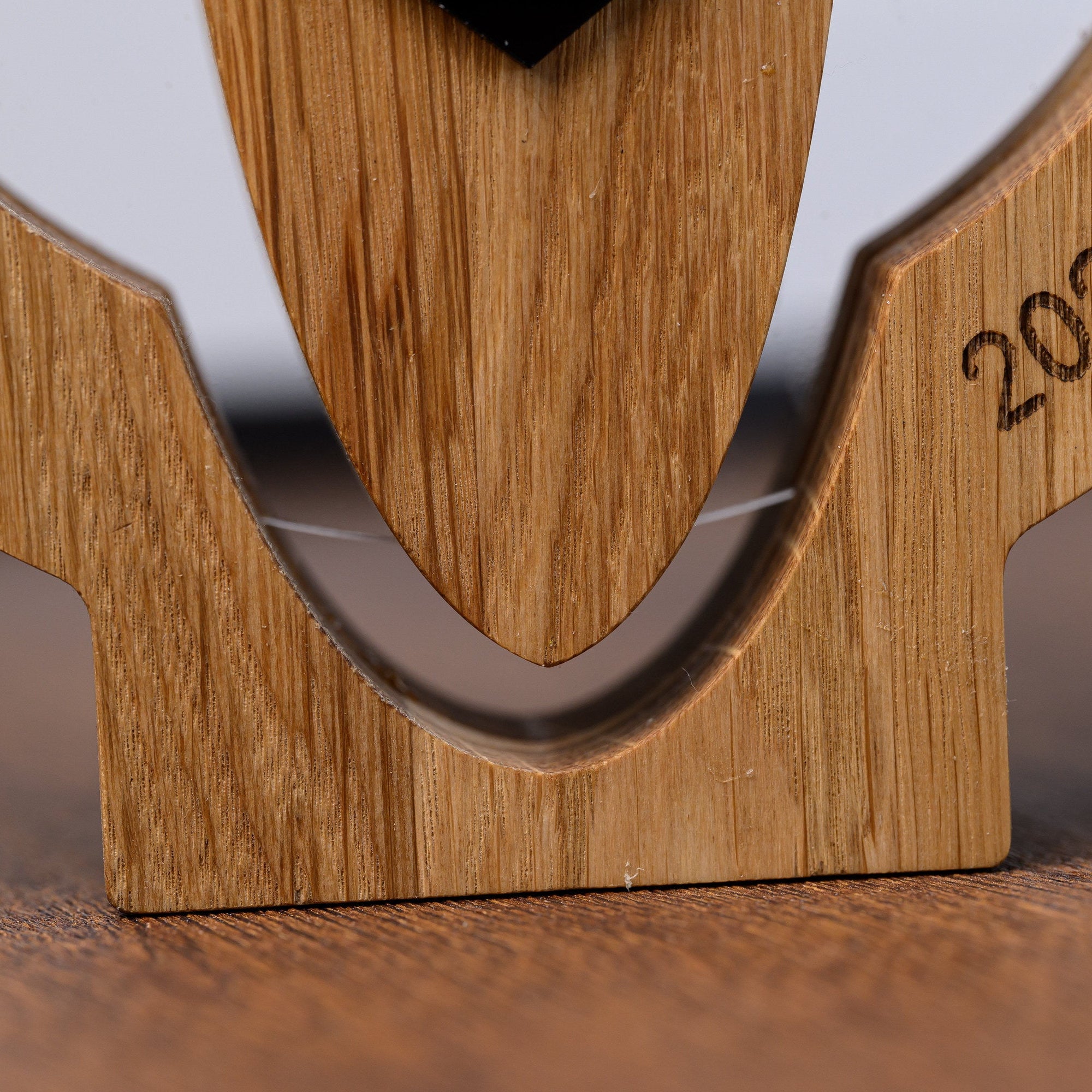 Oak base of the surf trophy resting on a wooden surface with the acrylic board slotted between arms