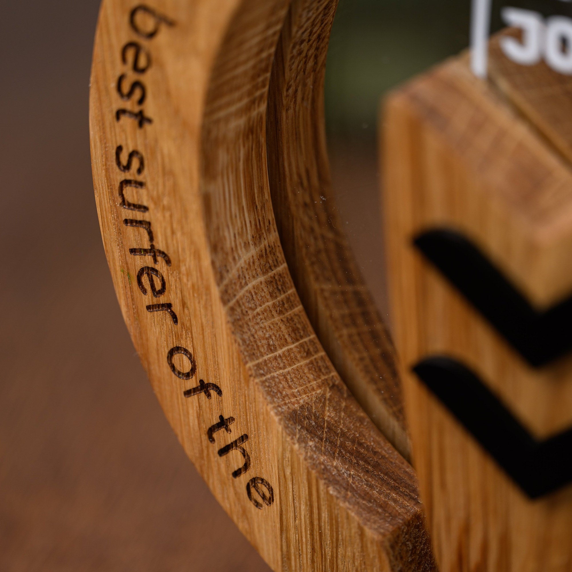 Laser engraved award title curving along the oak ring beside the black chevron detail of the trophy