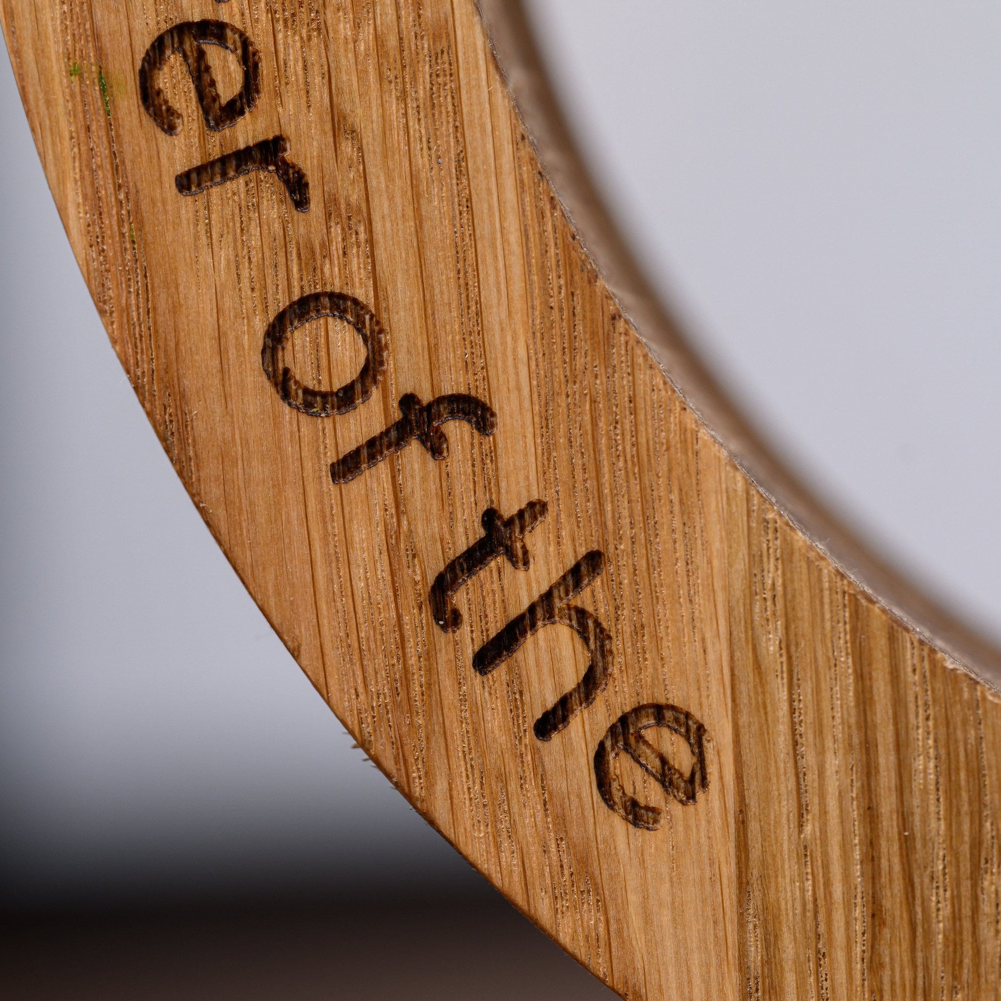 Macro shot of laser engraved lettering cut into the oak ring, showing grain texture and burn depth