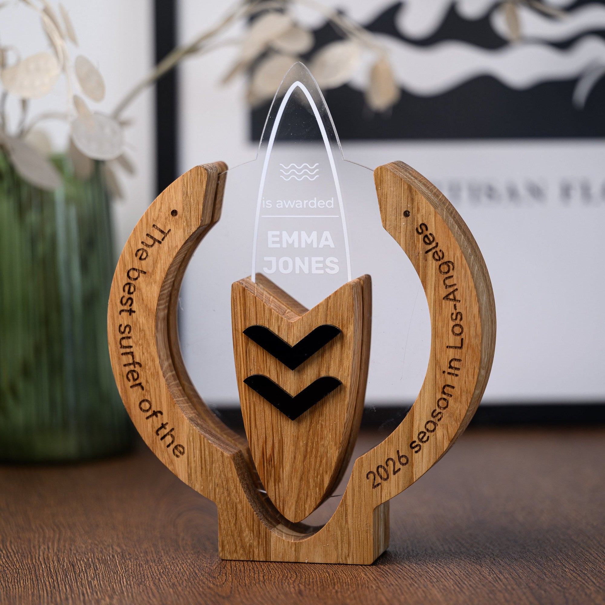 Custom surfing trophy with engraved oak frame and clear acrylic surfboard standing on a wooden desk