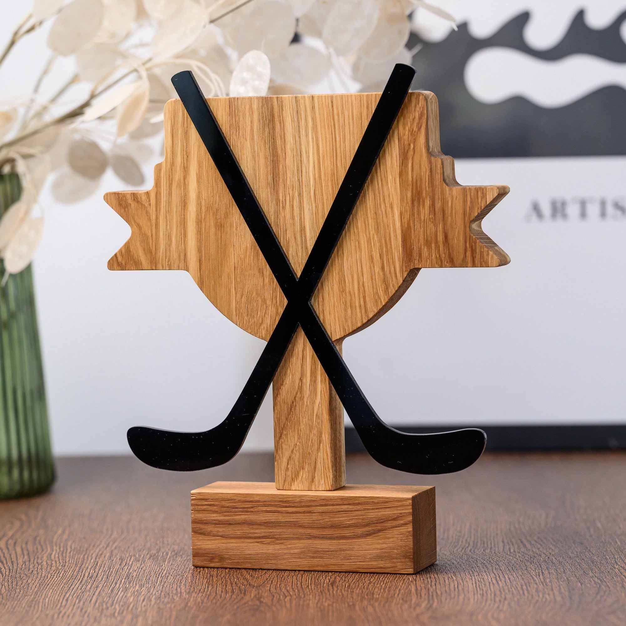 Reverse of the hockey trophy with plain oak cup shape and two black acrylic sticks crossing over it